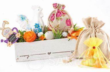 Bunte Osterkomposition aus Stoffbeuteln und einem rechteckigen Blumentopf mit gefärbten Ostereiern