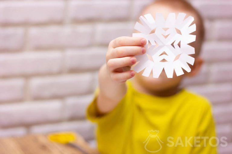 Kind schneidet eine Schneeflocke aus Papier aus