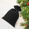 Schwarze Samtbeutel für Weihnachtsgeschenke wunderschön dekoriert mit Tannenzweigen.