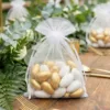 Elegante Deko-Beutel 10x13 auf dem Hochzeitstisch zwischen grünen Blättern.
