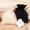 Set aus schwarzen und naturfarbenen Baumwollsäckchen mit Baumwollzweig.