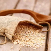 Kleiner Leinensack mit GetreidefĂŒllung auf rustikalem Holzgrund mit Holzlöffel