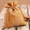 Verschlossener kleiner Jutebeutel naturfarben mit Kordelzug auf Holztisch