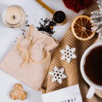 Jutesäckchen auf winterlich dekoriertem Tisch mit Teeblättern und Schneeflocken