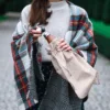 Person mit Decke hält Trinkflasche in einem großen Jutesack im Freien