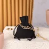 Schwarzer Samtbeutel für Schmuck mit goldenem Armband und Glitzersteinen auf hellem Untergrund.