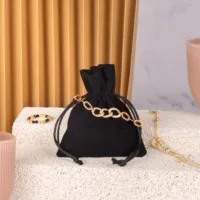 Schwarzer Samtbeutel für Schmuck mit goldenem Armband und Glitzersteinen auf hellem Untergrund.