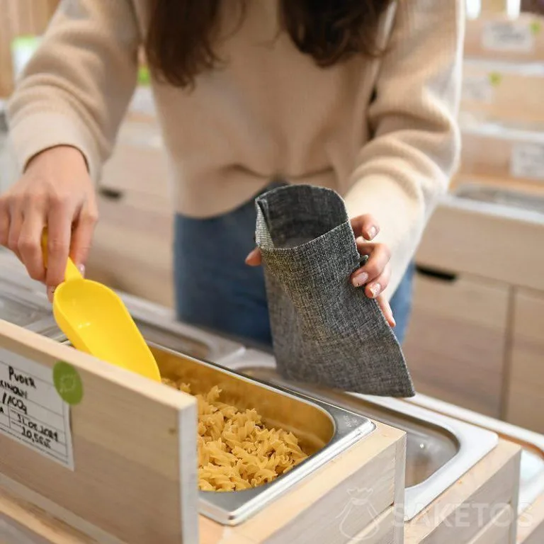 Frau kauft ein, indem sie lose Produkte in haltbare Einkaufstaschen packt - wiederverwendbare Juteverpackungen