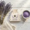 Lavendelsäckchen mit Bienen-Motiv neben getrocknetem Lavendelstrauß und violettem Badesalz