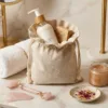 Leinen Säckchen mit Kosmetikprodukten und Handtuch auf einem Marmorregal im Badezimmer