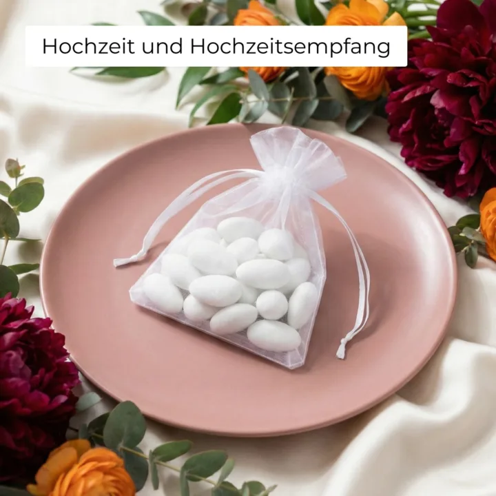 Weißer Organzabeutel mit Mandeln auf einem Teller als Gastgeschenk.